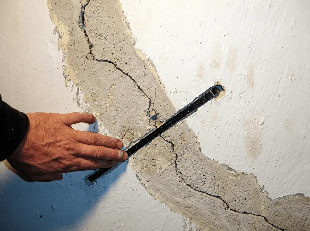 A wall with a large crack is being inspected by a professional in Riverside, CA