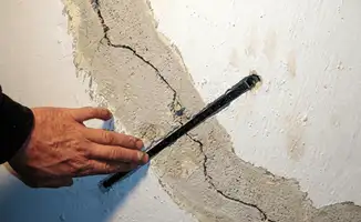 A wall with a large crack is being inspected by a professional in Riverside, CA